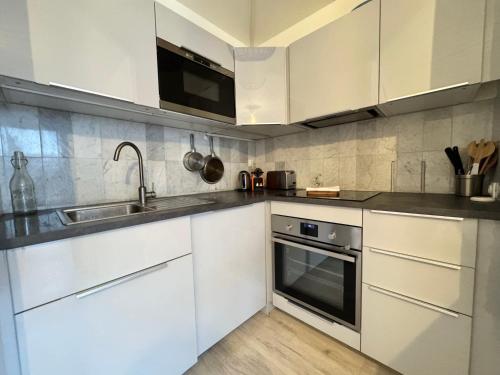 a kitchen with white cabinets and a sink at Le Nantais, centre de Rennes avec garage privé in Rennes