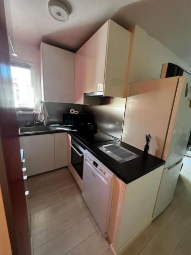 une cuisine avec des armoires blanches et un comptoir noir dans l'établissement Appartement Hyeres 10 min plage, à Hyères