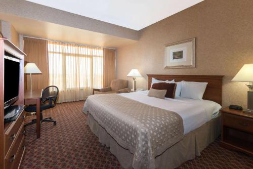 a hotel room with a large bed and a television at Ramada by Wyndham Topeka Downtown Hotel & Convention Center in Topeka