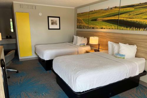 a hotel room with two beds and a painting on the wall at Days Inn by Wyndham Hays in Hays