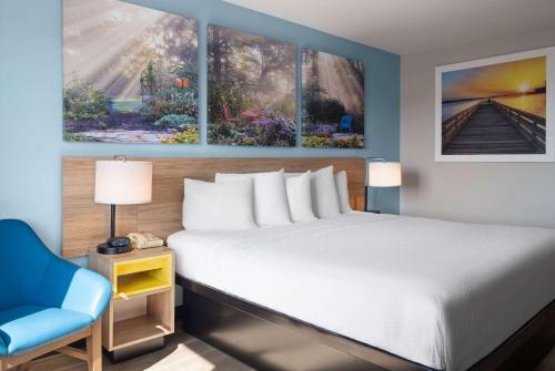 a bedroom with a large bed and a blue chair at Days Inn by Wyndham Neenah in Neenah