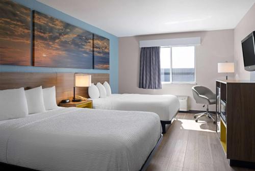a hotel room with two beds and a television at Days Inn by Wyndham Neenah in Neenah