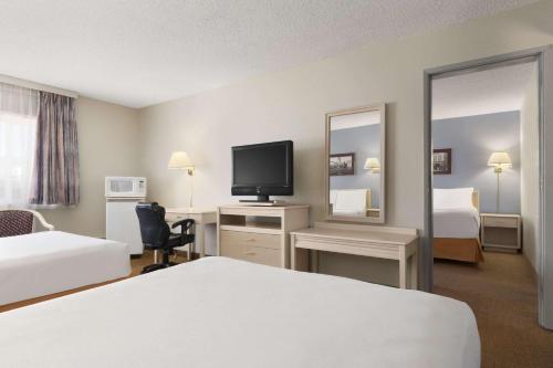 a hotel room with a bed and a desk with a television at Travelodge by Wyndham Calgary South in Calgary