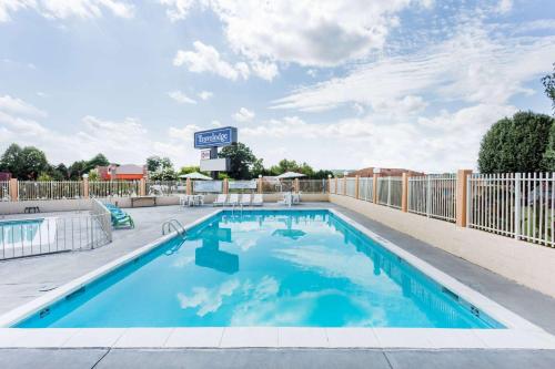 a swimming pool with a fence and a basketball hoop at Travelodge by Wyndham Ridgeway Martinsville Area in Martinsville