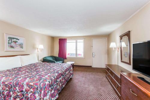a hotel room with a bed and a flat screen tv at Travelodge by Wyndham Ridgeway Martinsville Area in Martinsville