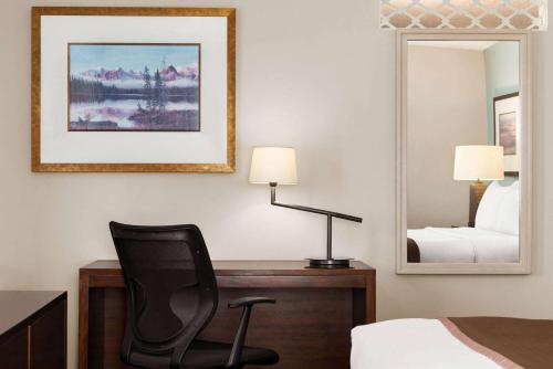 a bedroom with a desk and a chair and a mirror at Travelodge by Wyndham Calgary South in Calgary