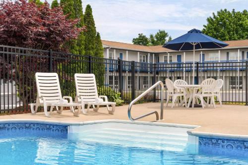 a pool with chairs and a table and an umbrella at Days Inn by Wyndham Middletown/Newport Area in Middletown