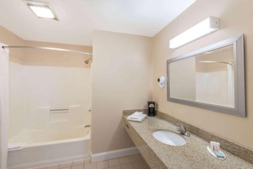 a bathroom with a sink and a tub and a mirror at Days Inn by Wyndham Middletown/Newport Area in Middletown