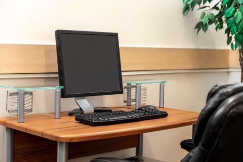 a computer monitor and a keyboard on a desk at Travelodge by Wyndham Calgary South in Calgary