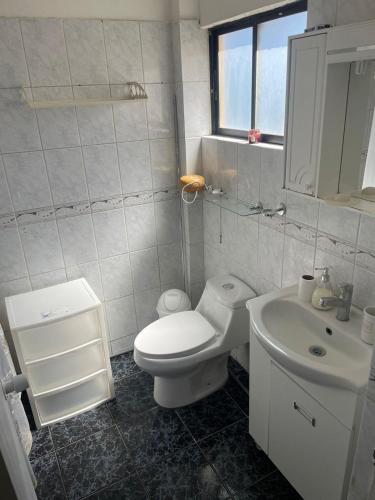 a white bathroom with a toilet and a sink at Casa en condominio equipada para 8 personas in Calama