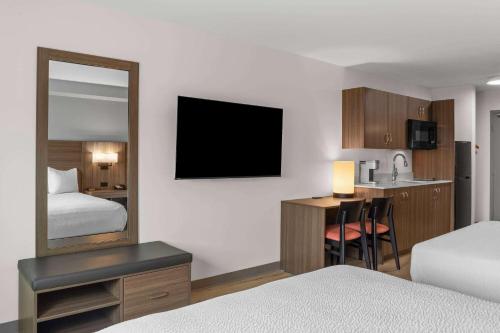 a hotel room with a bed and a desk with a mirror at Days Inn by Wyndham Steinbach in Steinbach