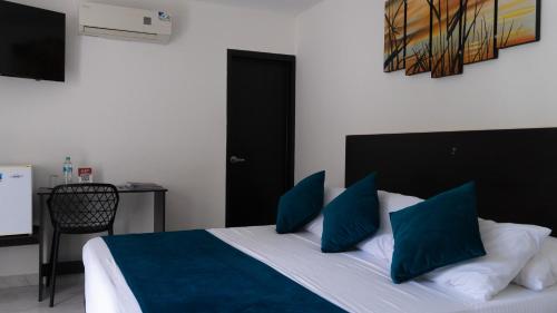a bedroom with a bed with blue pillows and a table at Hotel Campestre Santa Catalina in San Gil