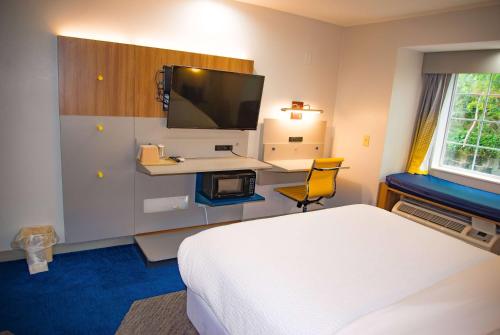 a hotel room with a bed and a flat screen tv at Microtel Inn & Suites by Wyndham Daphne in Daphne
