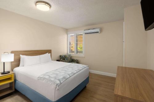 a bedroom with a large bed and a window at Days Inn by Wyndham Maui Oceanfront in Wailea