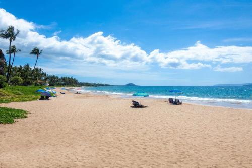 a beach with chairs and umbrellas and the ocean at Days Inn by Wyndham Maui Oceanfront in Wailea
