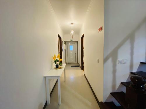 a hallway with a white table and flowers on it at Alojamento CANTO NA RELVA in Ponta Delgada