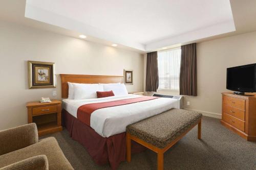 a hotel room with a bed and a flat screen tv at Travelodge by Wyndham Spruce Grove in Spruce Grove