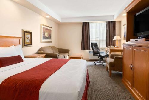 a hotel room with a bed and a desk at Travelodge by Wyndham Spruce Grove in Spruce Grove