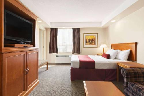 a hotel room with a bed and a flat screen tv at Travelodge by Wyndham Spruce Grove in Spruce Grove
