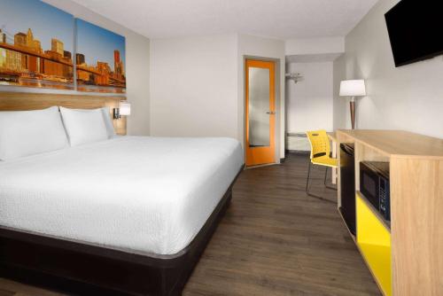 a hotel room with a bed and a desk at Days Inn & Suites by Wyndham Albany in Albany