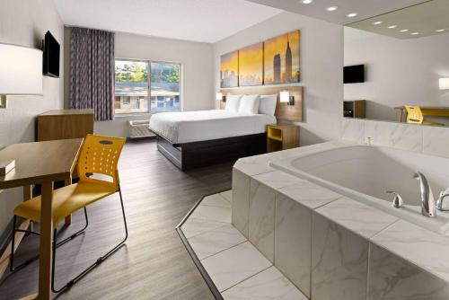 a hotel room with a bed and a tub at Days Inn & Suites by Wyndham Albany in Albany