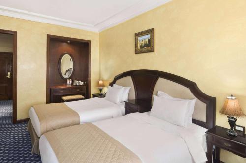 a hotel room with two beds and a mirror at Ramada By Wyndham Fes in Fès
