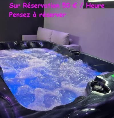 a hot tub with blue water in a room at Gîtes Rozanna avec accès détente SPA JACUZZI in Saint-Jean-de-la-Rivière