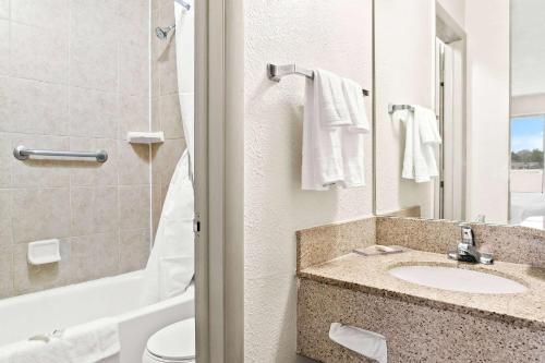 a bathroom with a sink and a toilet and a mirror at Days Inn & Suites by Wyndham Warren in Warren