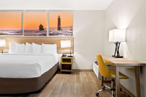 a hotel room with a bed and a desk and a desk at Days Inn & Suites by Wyndham Warren in Warren