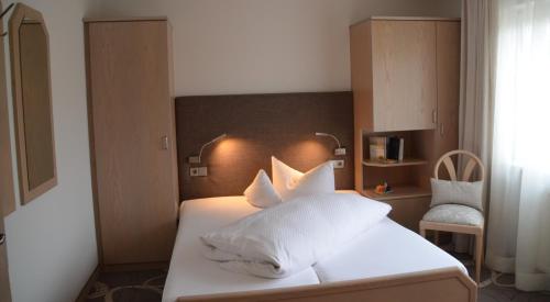 a bedroom with a bed with white sheets and pillows at Castell Hotel & Restaurant in Leinsweiler