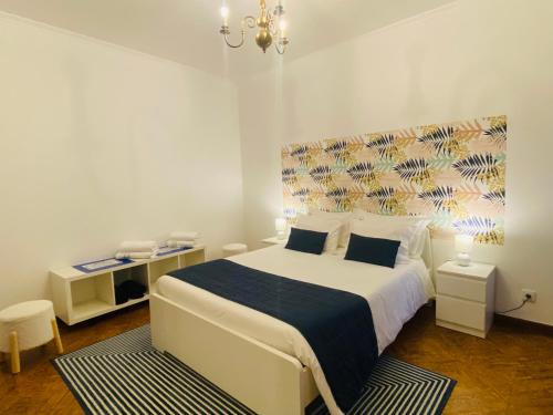 a bedroom with a large white bed with a blue blanket at Alojamento CANTO NA RELVA in Ponta Delgada