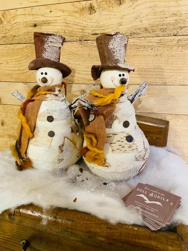 two snowmen sitting next to each other in snow at Residenza dell'Aquila - appartamento in Vezza dʼOglio