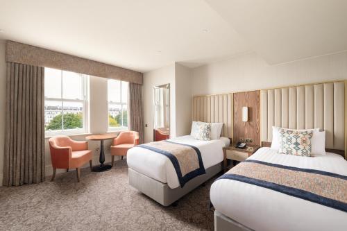 a hotel room with two beds and a desk at voco The Clifton Folkestone by IHG in Folkestone