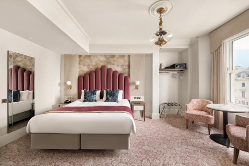 a bedroom with a large bed with a red headboard at voco The Clifton Folkestone by IHG in Folkestone