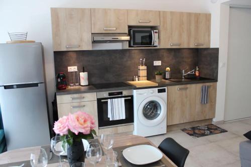 une cuisine avec un lave-linge et un micro-ondes dans l'établissement Appartement T2 cosy - Embrun, à Embrun