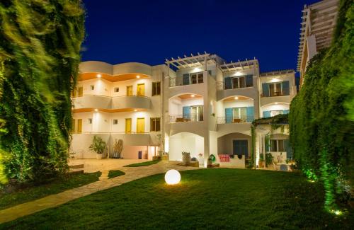 a large white building with a yard at night at Oasis Beach Hotel in Skala