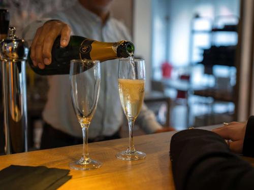 a man pouring champagne into two glasses on a table at ibis Epernay Centre Ville in Épernay