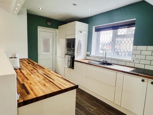a kitchen with white cabinets and a wooden counter top at Three bedroom village home, near Grimsby and Cleethorpes in Waltham