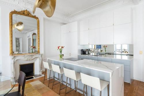 - une cuisine avec un bar avec des placards blancs et un miroir dans l'établissement Luxury High End Condo in the Heart of Paris, à Paris