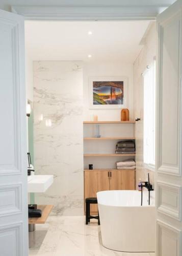 une salle de bain blanche avec une baignoire et un lavabo dans l'établissement Luxury High End Condo in the Heart of Paris, à Paris