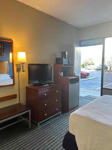 a hotel room with a bed and a flat screen tv at Days Inn by Wyndham Virginia Beach At The Beach in Virginia Beach