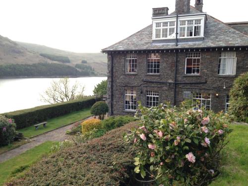 an old house on a hill next to a lake at Haweswater Hotel in Bampton