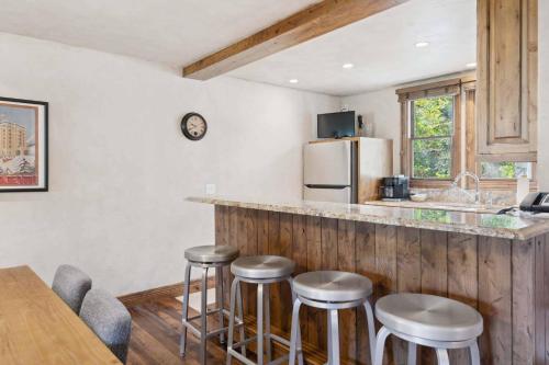 a kitchen with a counter with stools and a refrigerator at Woodrun Place 11 in Snowmass