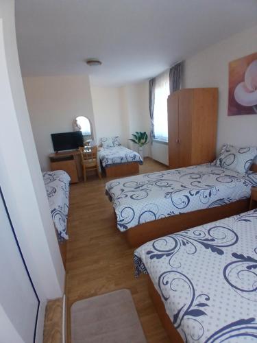 a room with three beds and a desk with a television at Guest rooms Bansko in Bansko