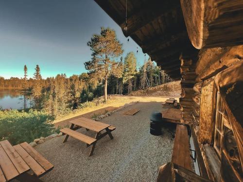 a wooden bench sitting outside of a cabin next to a lake at ÖBois Charlevoix - L'Écurie 4 Studio in Saint-Siméon