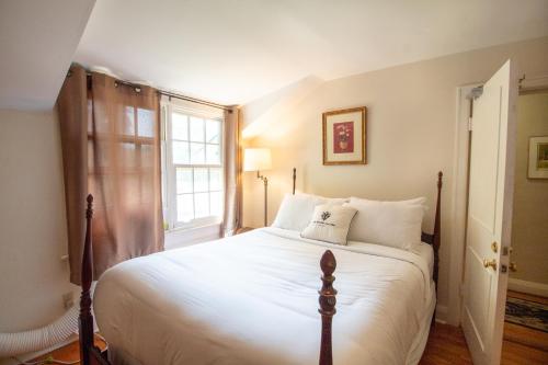 a bedroom with a bed with white sheets and a window at Hochelaga Inn in Kingston