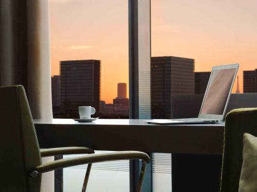 a desk with a laptop and a cup of coffee at Pullman Paris Centre - Bercy in Paris