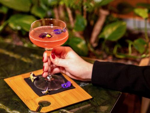 a person holding a martini glass on a table at Pullman Paris Centre - Bercy in Paris