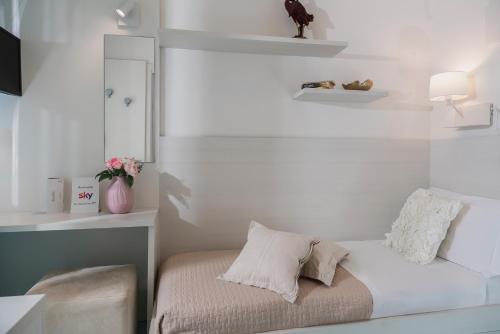 a white bedroom with a bed and a mirror at Hotel Ca' Bianca in Riccione