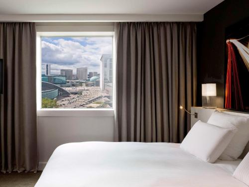 a hotel room with a large window with a view at Pullman Paris La Défense in Courbevoie